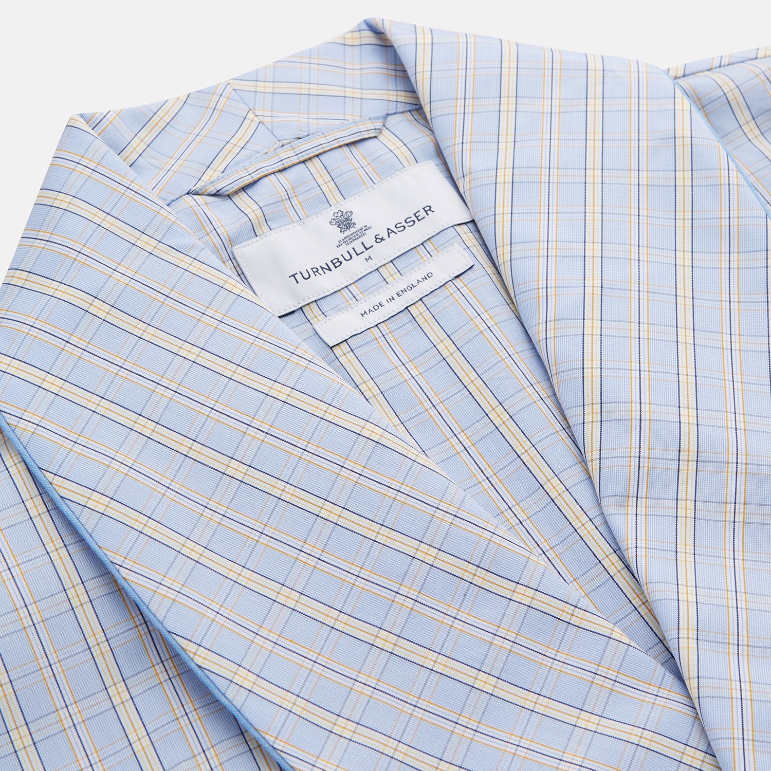 View 2 of product The Turnbull & Asser Blue and Yellow Check Poplin Cotton Dressing Gown features long sleeves, a shawl collar, front pockets, and a matching belt at the waist, shown on a plain white background.