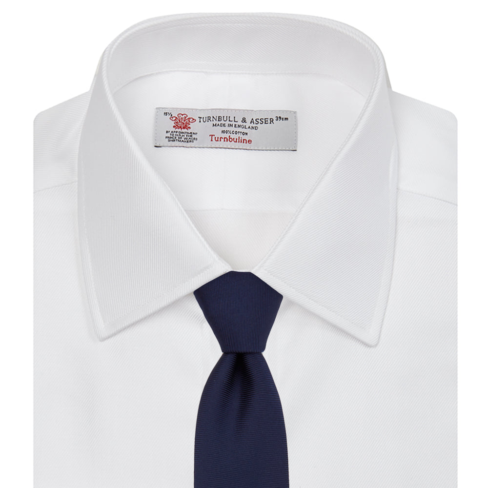 A neatly folded Turnbull & Asser White Oxford Shirt with T&A collar and double cuffs is displayed on a light blue background.