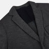View 2 of product The Turnbull & Asser Graphite Knitted Oxford Blazer for men features a dark gray hue, two buttons, notched lapels, and three front pockets—a modern British-inspired piece styled elegantly against a light background.