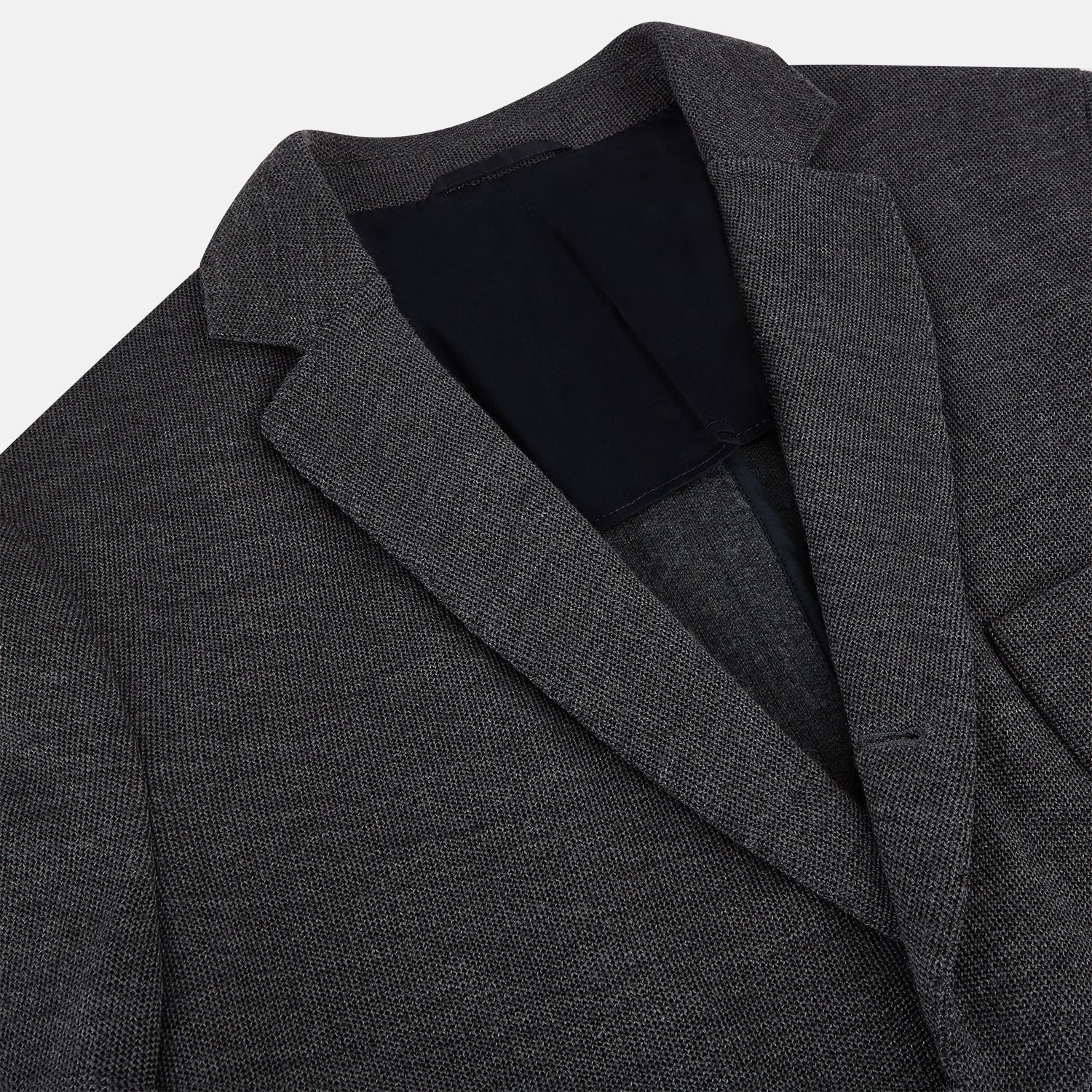 View 2 of product The Turnbull & Asser Graphite Knitted Oxford Blazer for men features a dark gray hue, two buttons, notched lapels, and three front pockets—a modern British-inspired piece styled elegantly against a light background.