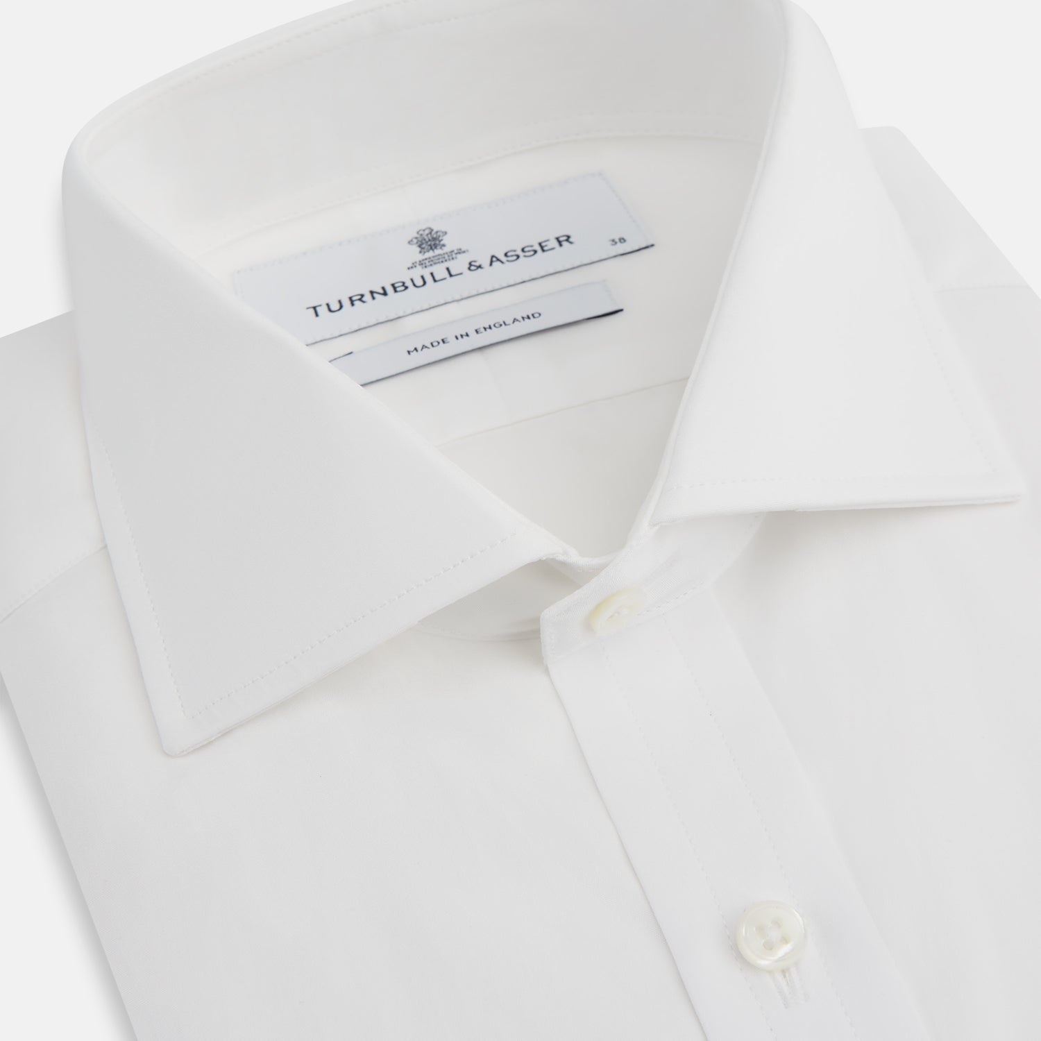 View 2 of product The Turnbull & Asser White Poplin Shirt With Regent Collar and 2-Button Cocktail Cuffs, featuring long sleeves, is buttoned up and laid flat on a white background.