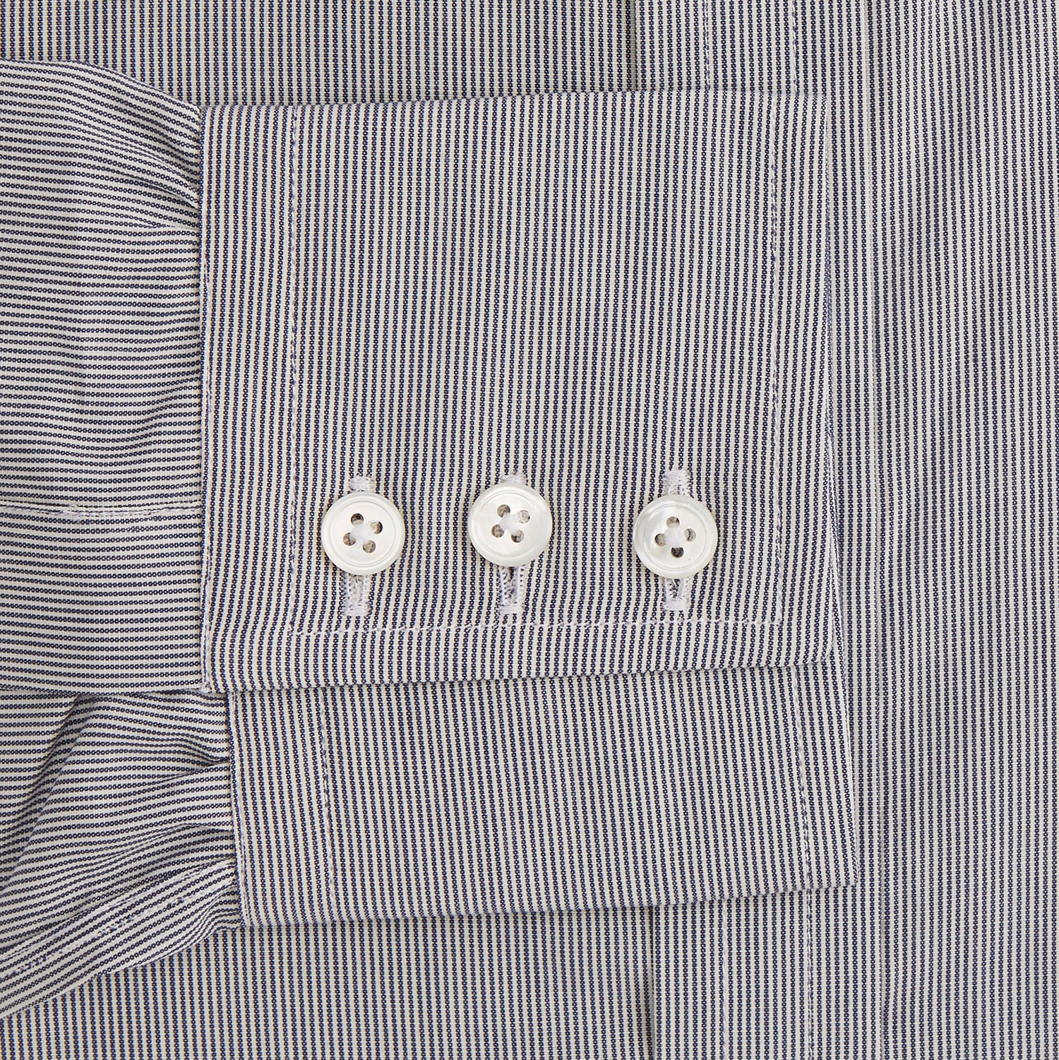 View 4 of product The Turnbull & Asser Navy Fine Stripe Mayfair Shirt, a long-sleeve, button-up with a classic collar, features fine navy stripes and white buttons, shown laid flat on a white background.