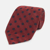 View 1 of product A Turnbull & Asser Navy Dot and Red Silk Tie, featuring a diagonal herringbone pattern with evenly spaced navy blue polka dots, is rolled up on a white background.
