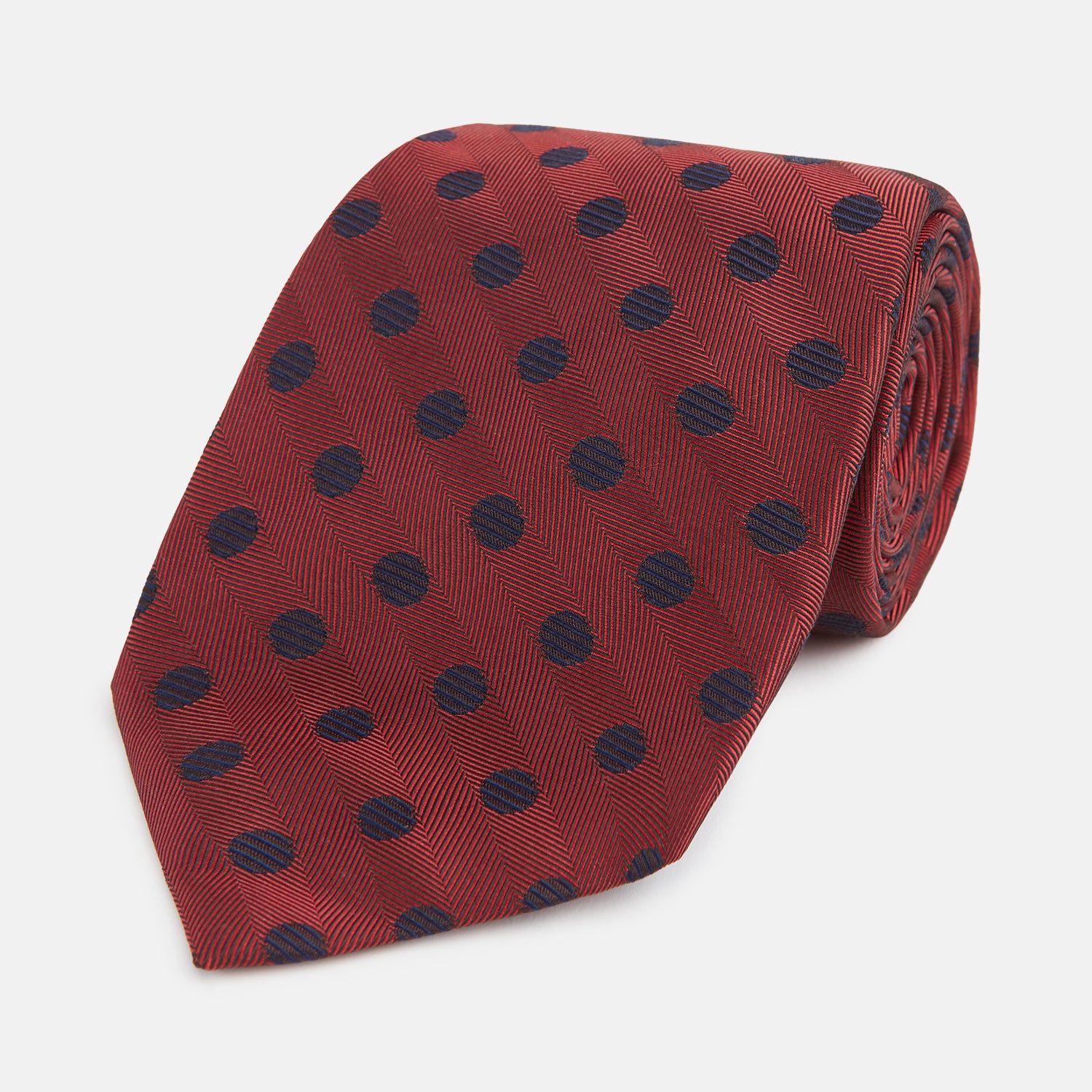 View 1 of product A Turnbull & Asser Navy Dot and Red Silk Tie, featuring a diagonal herringbone pattern with evenly spaced navy blue polka dots, is rolled up on a white background.