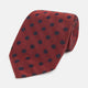 A Turnbull & Asser Navy Dot and Red Silk Tie, featuring a diagonal herringbone pattern with evenly spaced navy blue polka dots, is rolled up on a white background.
