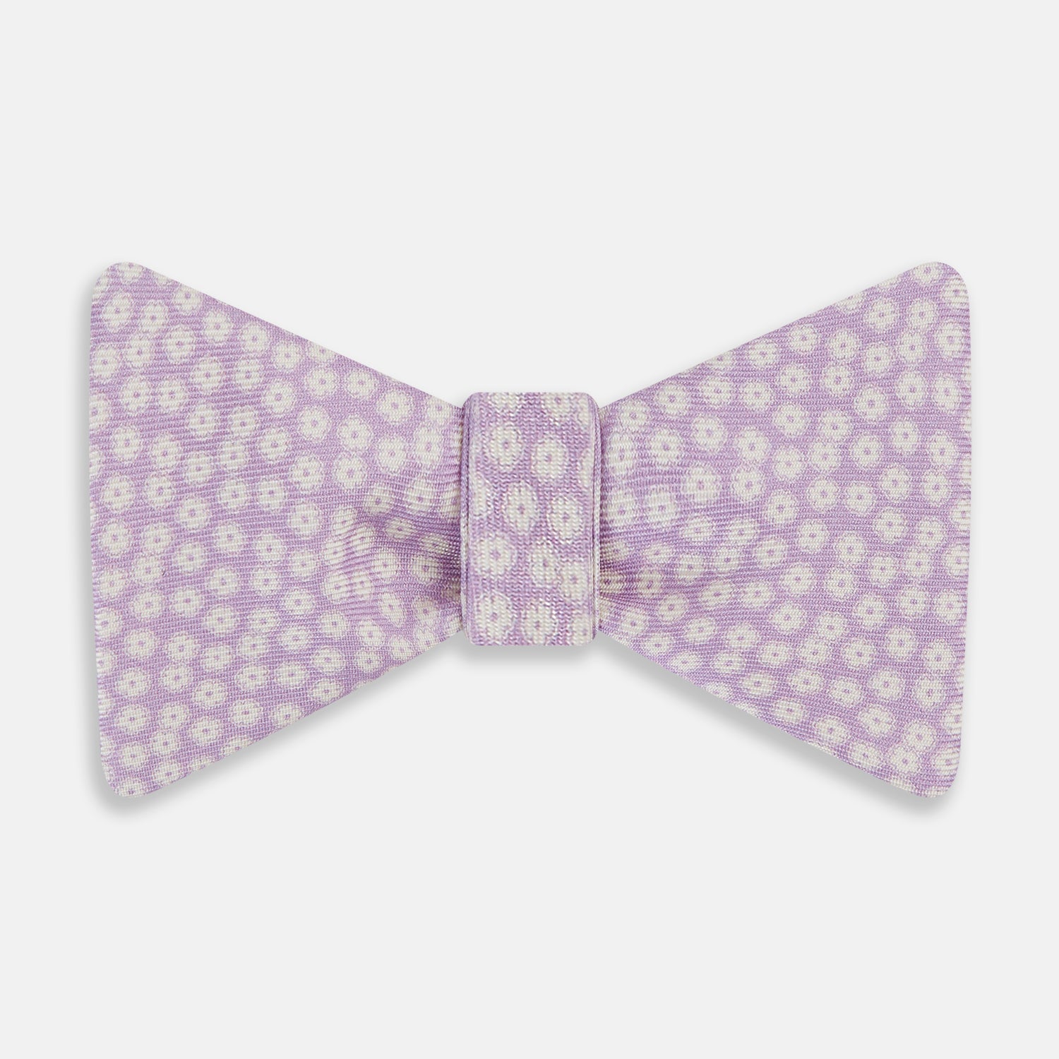 View 1 of product The Turnbull & Asser Lilac Flower Patterned Silk Bow Tie showcases small white flowers on lilac silk, making it a refined accessory for smart outfits. Shown against a white background.