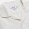 View 2 of product The Cream Silk Holiday Fit Phillips Shirt by Turnbull & Asser is a short-sleeved, collared silk shirt in off-white with three front pockets and a revere collar, displayed flat on a plain white background.
