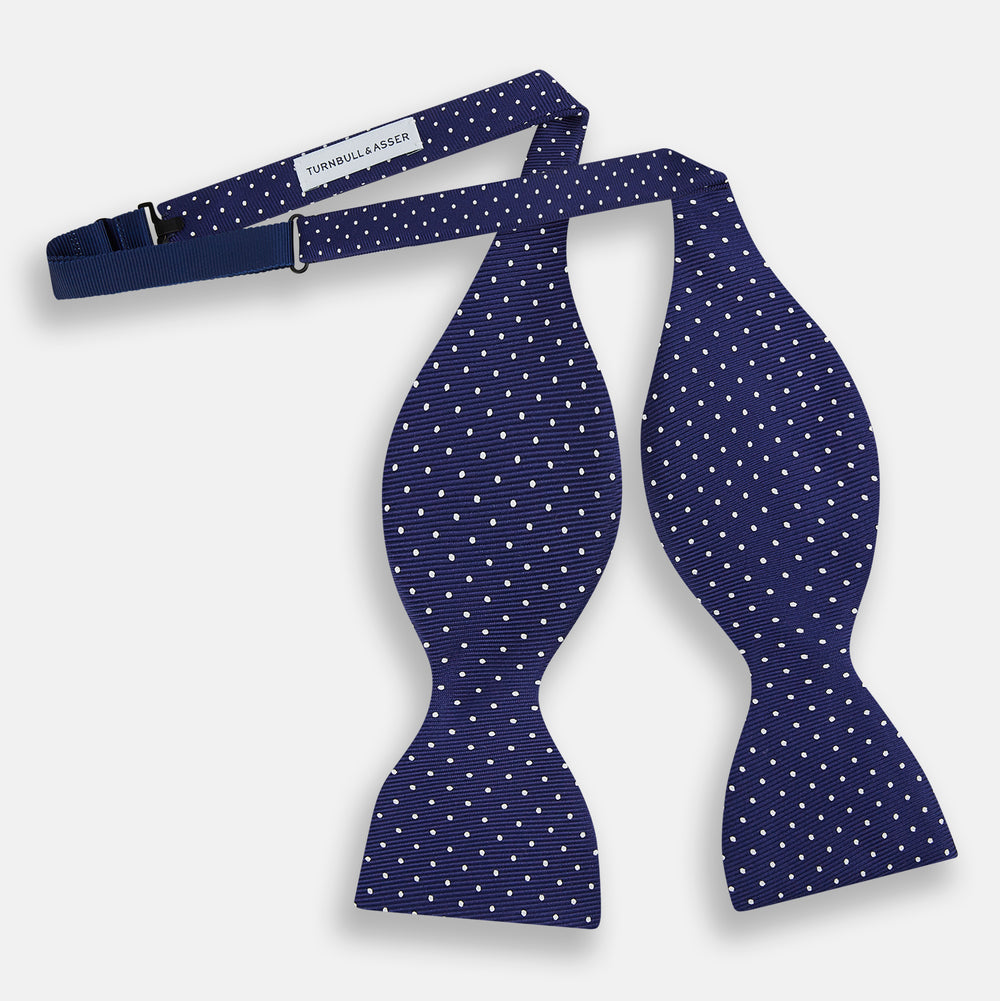 The Turnbull & Asser Azzurro and White Spot Silk Bow Tie features a classic blue silk design with small white spots, shown elegantly against a plain white background.