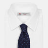 View 2 of product The LACE ON TONE SPOT NAVY FORD TIE by Turnbull & Asser is a rolled-up navy tie with textured fabric and an evenly spaced pattern of small light blue polka dots.