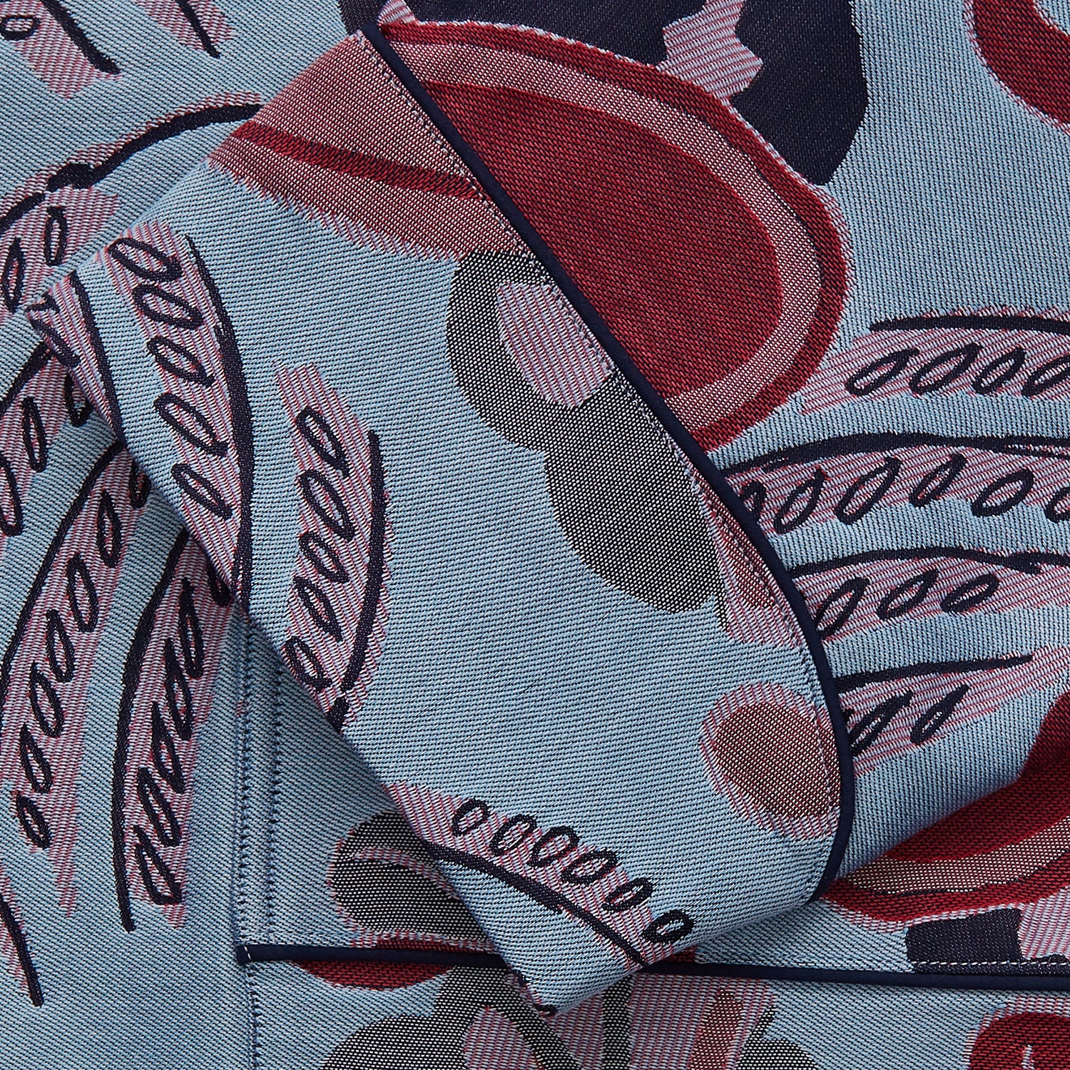 View 3 of product The Blue Paisley Pattern Cotton Arnold Gown by Turnbull & Asser features light blue jacquard cotton with a red and black paisley design, long sleeves, a matching belt, and two front pockets for a subtle Bloomsbury-inspired look.