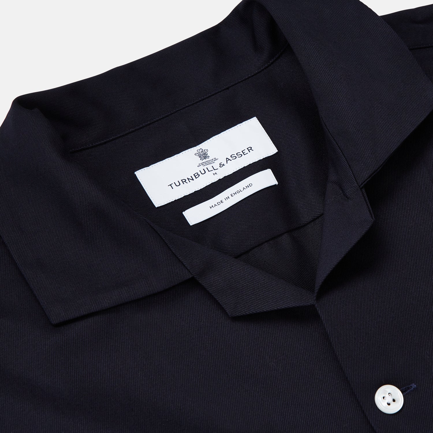 View 2 of product A Navy Cotton Holiday Fit Winnington Shirt by Turnbull & Asser, featuring long sleeves, a chest pocket, white buttons, and a revere collar, is laid flat on a white background.