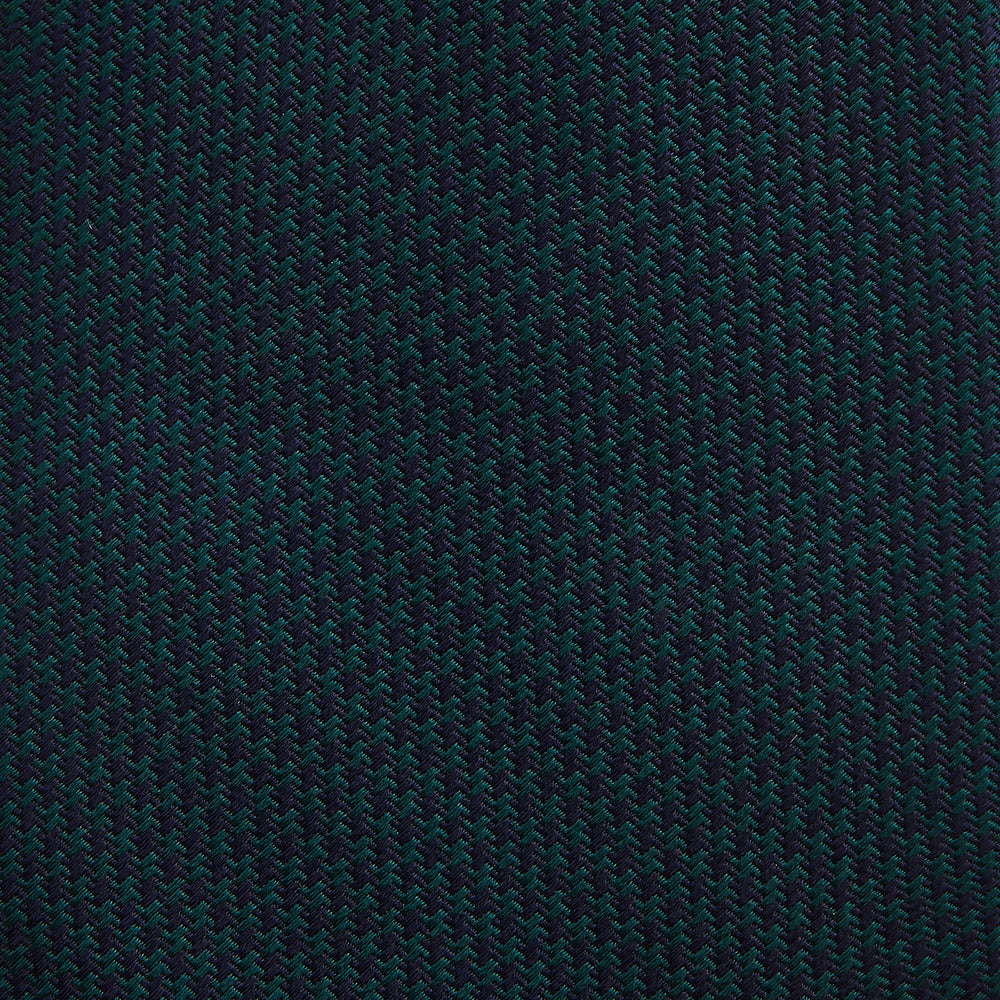 The Turnbull & Asser Navy Houndstooth Forest Green Tie is shown rolled up, featuring a subtle houndstooth pattern against a plain white background.