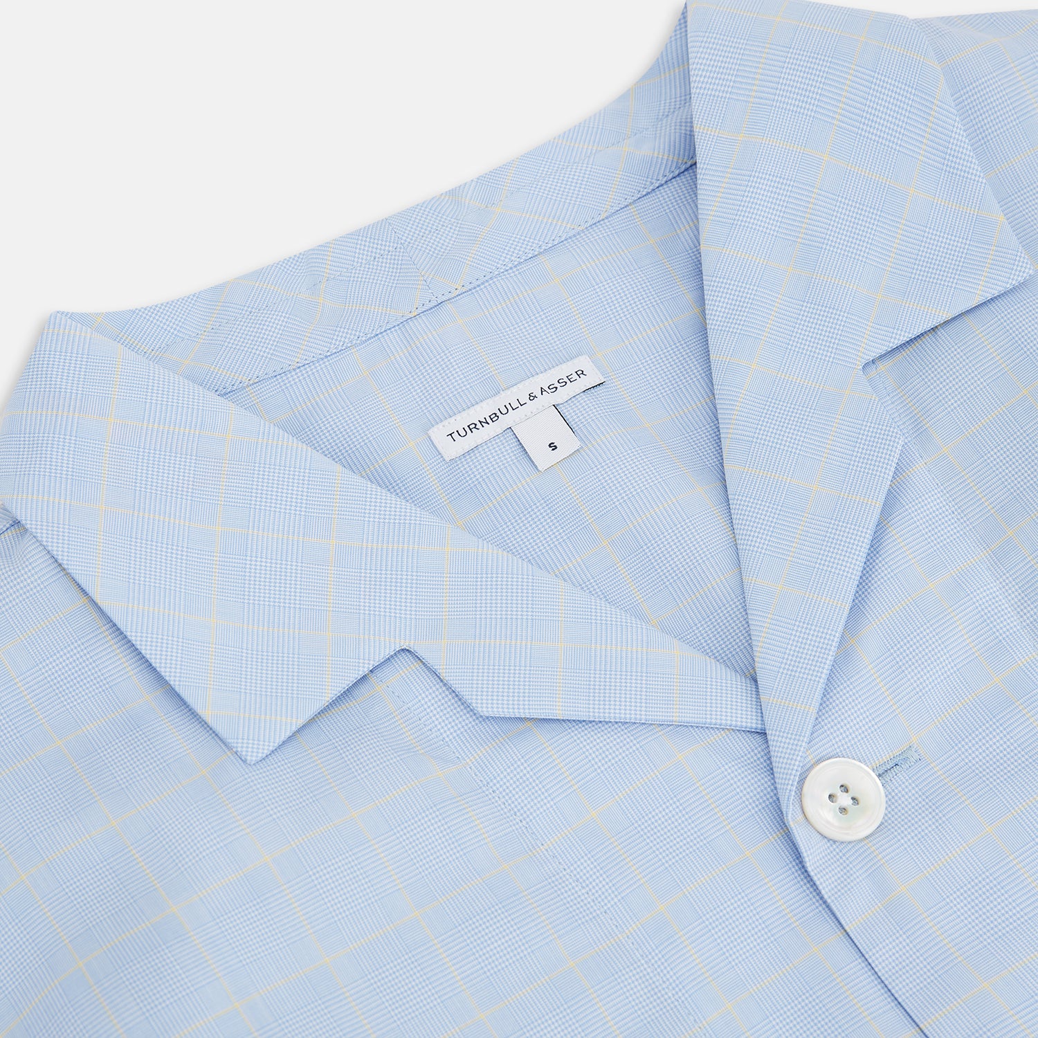 View 2 of product The Turnbull & Asser Blue Prince of Wales Check Pyjama Shirt features long sleeves, a notched collar, a left chest pocket, and a subtle check pattern, shown laid flat on a white background.