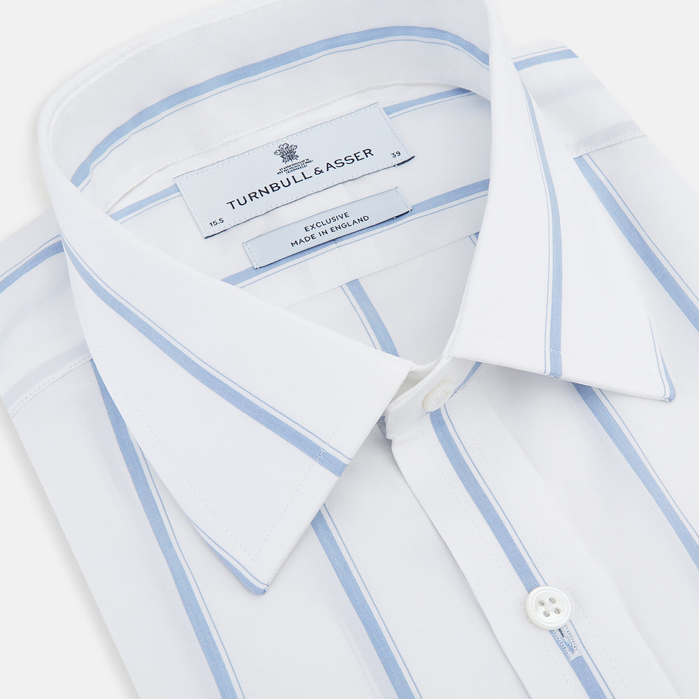 The Colony Blue Track Stripe Mayfair Shirt by Turnbull & Asser is a long-sleeve, button-up Italian cotton shirt with a white base and blue stripes, pointed collar, and buttoned cuffs, shown laid flat on a white background.