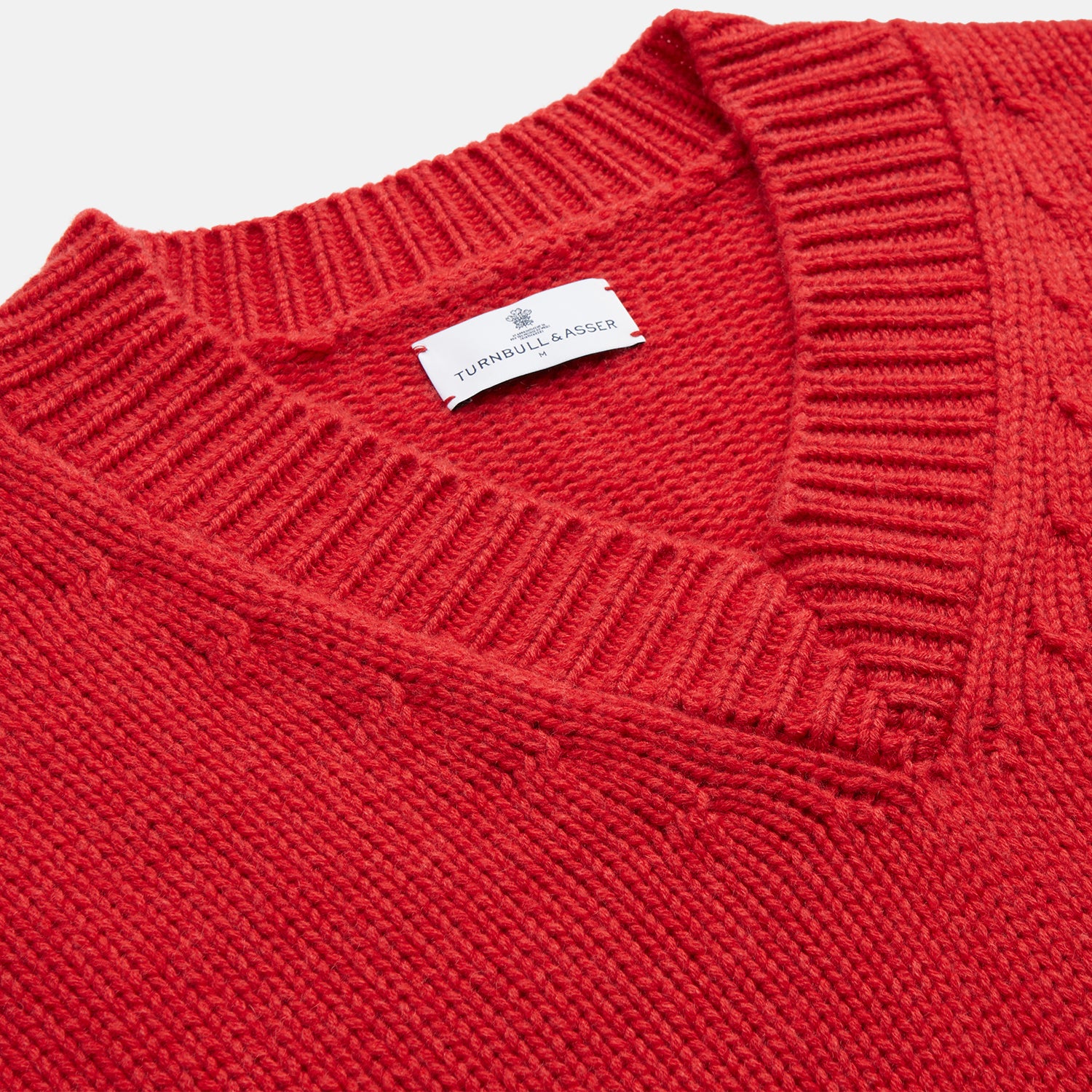 View 4 of product The Turnbull & Asser Raspberry Red Cashmere Edwards V-Neck Sweater features long sleeves, ribbed cuffs and hem, and is shown laid flat on a white background.