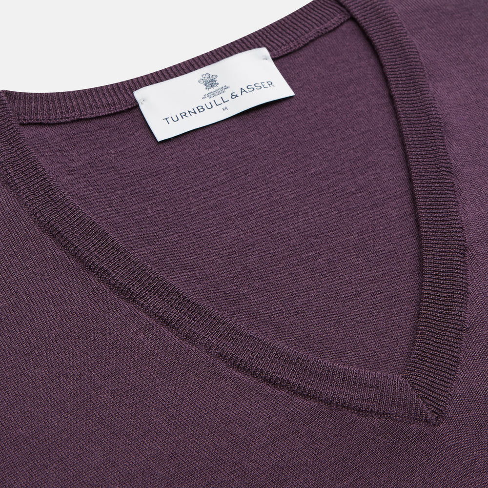 The Turnbull & Asser Plum Kennedy Merino V-Neck Jumper is a long-sleeved knitwear piece made from soft Italian wool, shown laid flat on a white background.