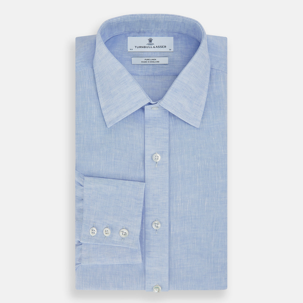 The Turnbull & Asser Pale Blue Linen Mayfair Shirt features a collar, front pocket, and white buttons. This long-sleeve shirt is displayed on a white background.