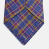 View 3 of product The Turnbull & Asser Blue Multi Tartan Silk Tie features a vibrant blue, yellow, and pink plaid pattern and is shown rolled up on a white background.