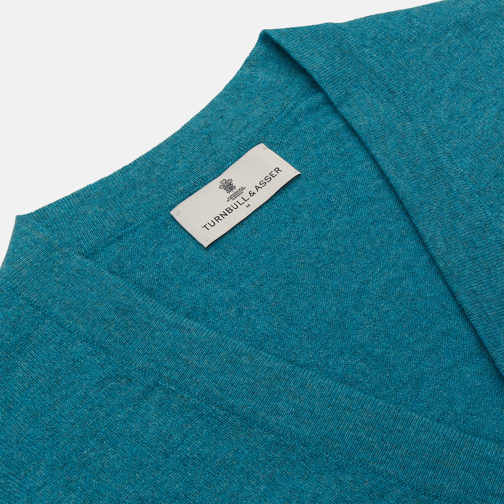 The Teal Lachlan Cashmere Cardigan by Turnbull & Asser features long sleeves, front pockets, and ribbed hem and cuffs. Displayed flat on a white background, this cozy piece is inspired by classic Scottish knitwear.