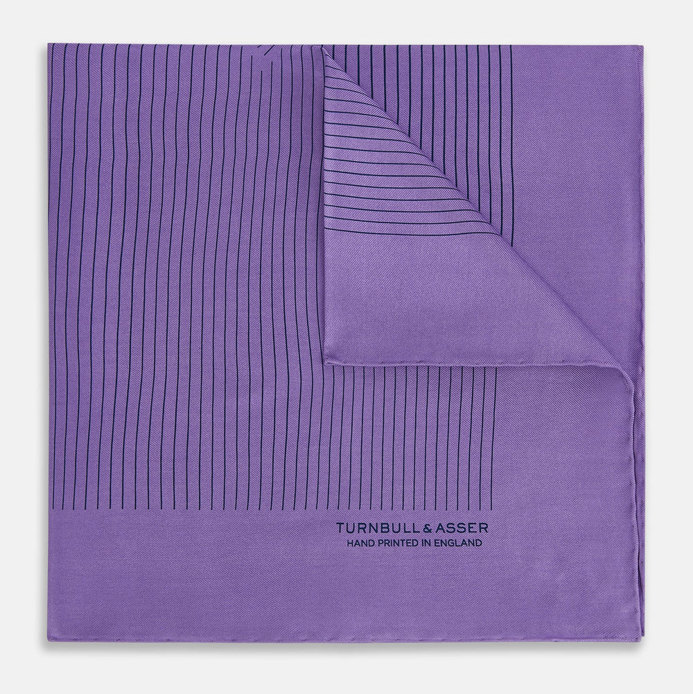 The Purple Stripe Silk Pocket Square by Turnbull & Asser features thin black lines on purple silk—a sophisticated blazer accessory hand printed in England, showcasing classic British craftsmanship.