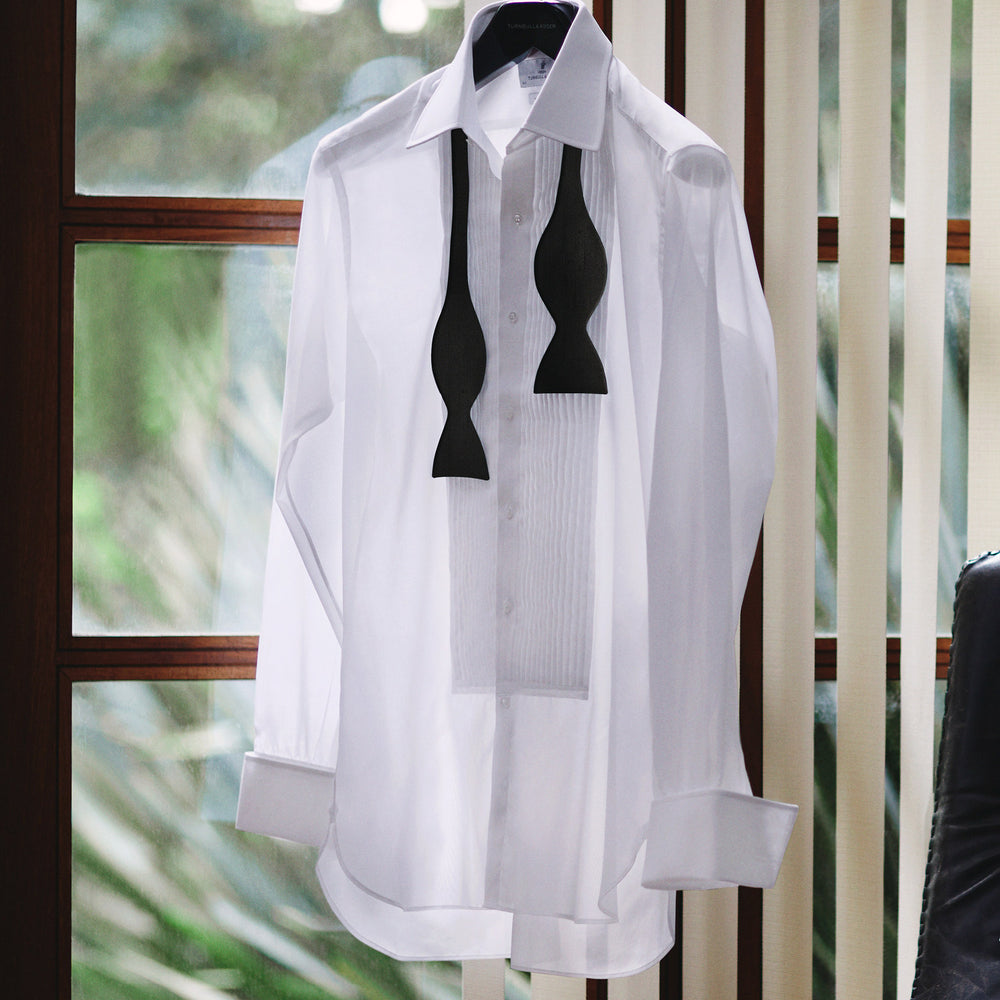 The Casino Royale Shantung Silk Bow Tie by Turnbull & Asser, as seen on James Bond, features a classic shape in black silk and is set against a plain white background—a timeless gentleman’s accessory.