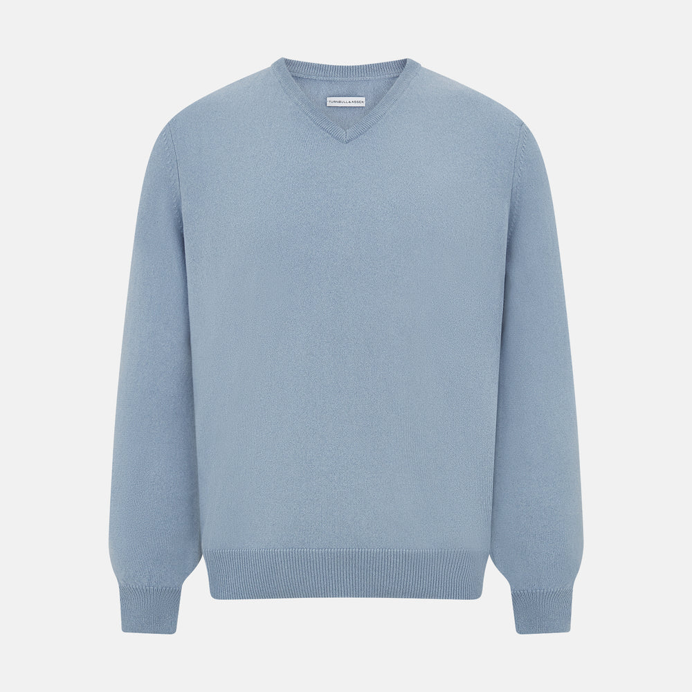 The Turnbull & Asser Frost Blue Cashmere V-Neck Jumper features ribbed cuffs, hem, and neckline. This elegant long sleeve knitwear piece is shown on a plain white background.