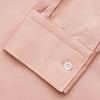 View 4 of product A man faces forward in a relaxed pose against a beige background, wearing the Turnbull & Asser Pink Piece Dyed Weekend Fit Suffolk Shirt with a button-down collar, dark cuffed jeans, and black shoes.