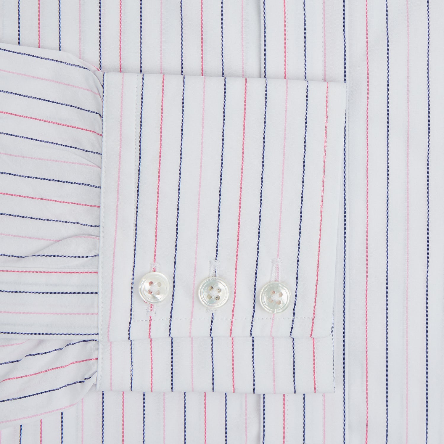 View 4 of product The Turnbull & Asser Pink and Blue Wide Pinstripe Mayfair Shirt features long sleeves, T&A collar, button-down front, and buttoned cuffs. It has bold pink and blue pinstripes on white and is laid flat on a white surface.