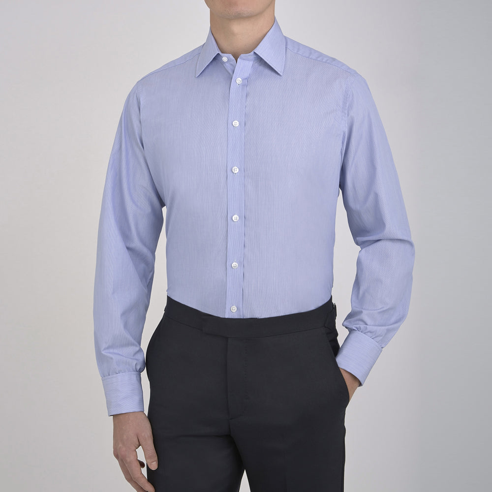 The Turnbull & Asser Blue Hairline Stripe Shirt features a T&A collar, 3-button cuffs, and white buttons. Made from light blue cotton with subtle stripes, it’s neatly folded with the label visible inside the collar on a plain white background.