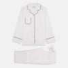 View 6 of product The Turnbull & Asser Women's Harriet Plain White Cotton Pyjama Set features long sleeves, black piping, a chest pocket, and matching pants with elastic waistband and ribbon tie, all displayed on a white background.
