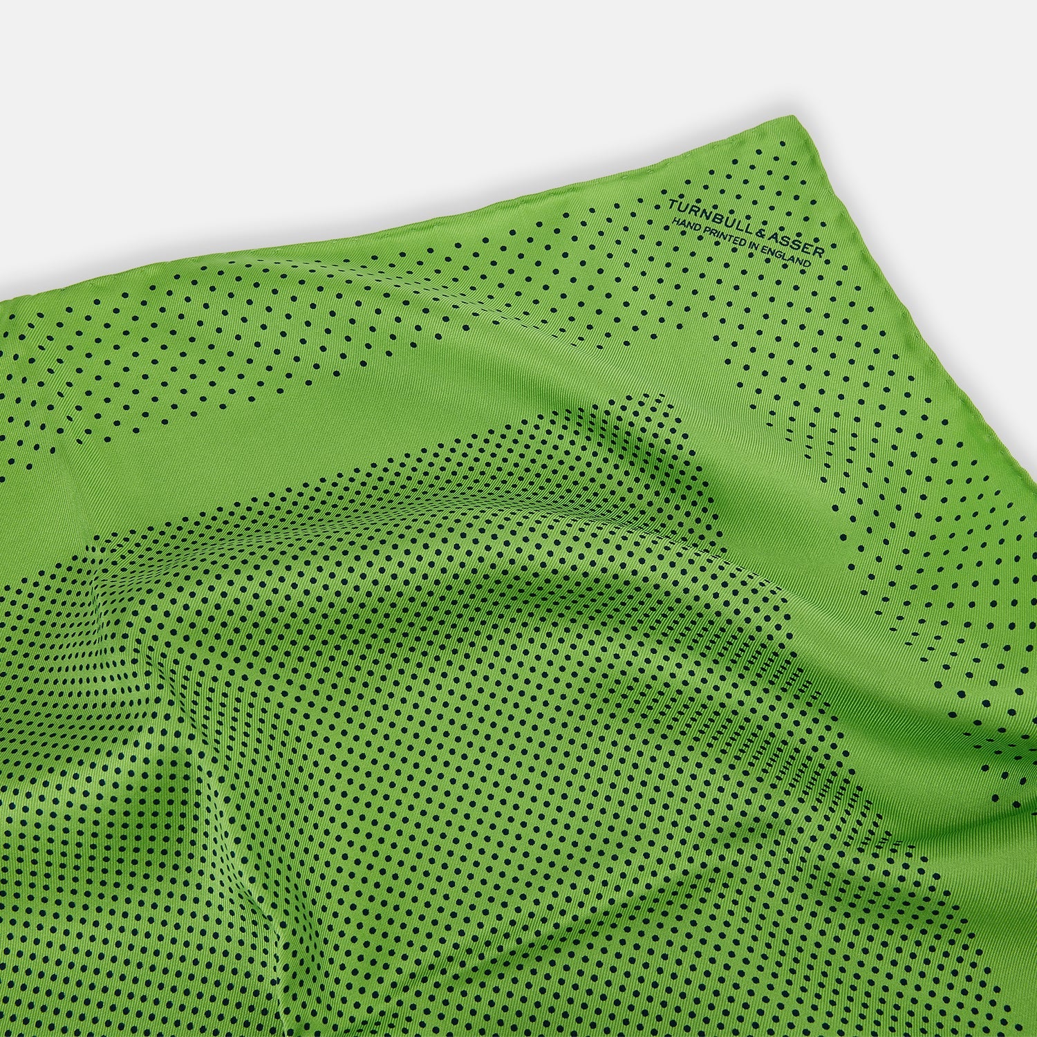 View 2 of product The Turnbull & Asser Kelly Green Dot Silk Pocket Square features small black polka dots and is shown neatly folded to showcase both its front and inner sides.