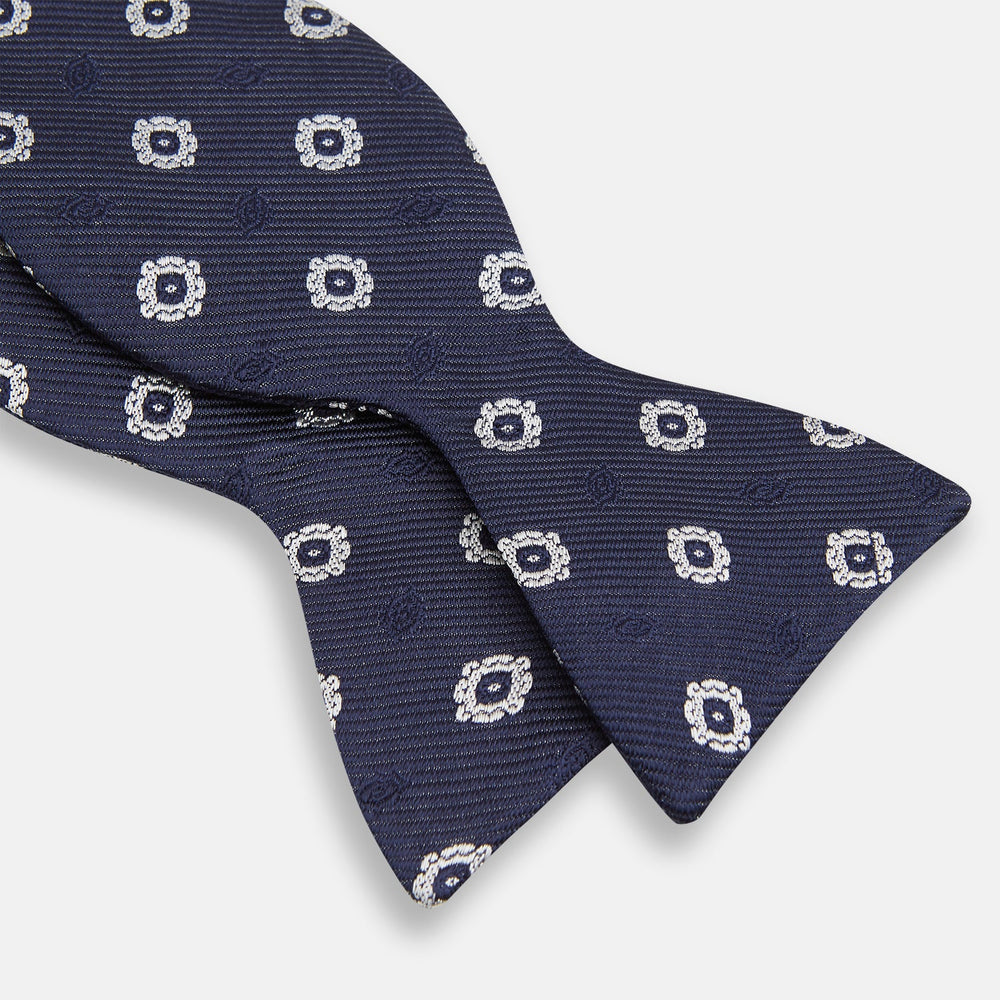 The Navy and White Motif Silk Bow Tie by Turnbull & Asser features a geometric floral pattern, adding refined elegance to formalwear. Shown on a plain white background.