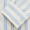 View 4 of product A man with short brown hair stands against a beige background in a Turnbull & Asser Blue and Off-White Stripe Cotton Weekend Fit Finch Shirt, featuring vertical stripes and a Derby collar, paired with dark pants. One hand is in his pocket; he has a neutral expression.