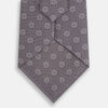 View 3 of product The Turnbull & Asser Ash Medallion Silk Tie features rolled-up ash silk with gray and light purple medallion and grid-like motifs on a white background.