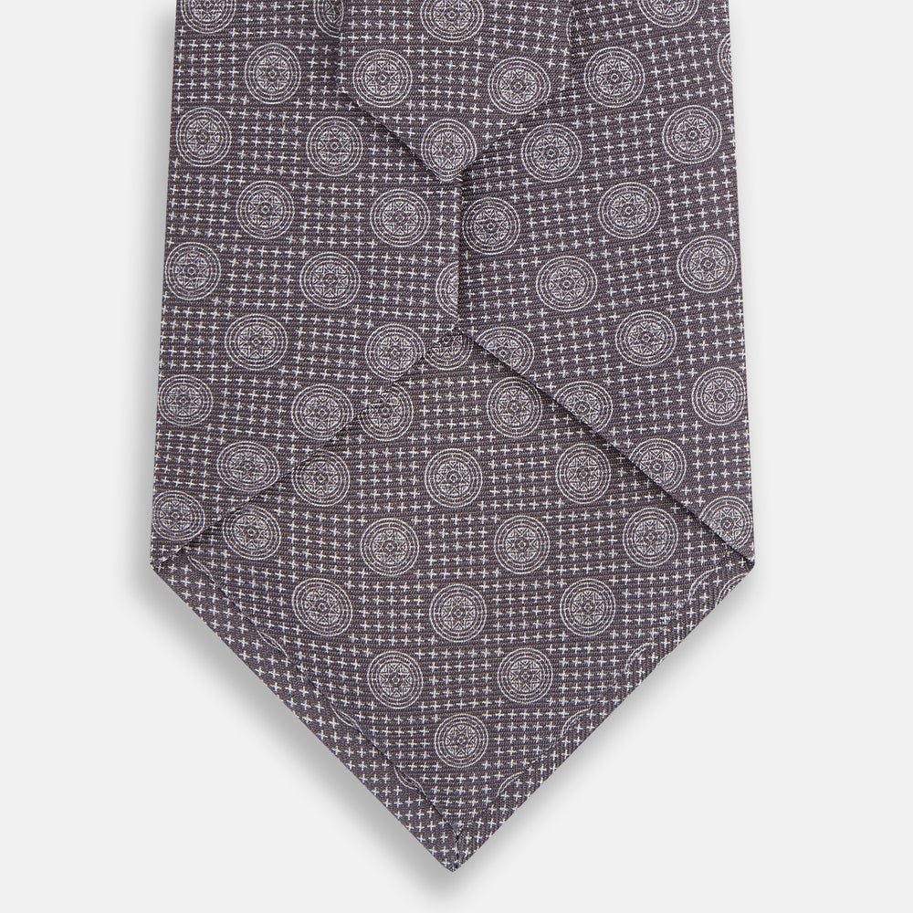 The Turnbull & Asser Ash Medallion Silk Tie features rolled-up ash silk with gray and light purple medallion and grid-like motifs on a white background.