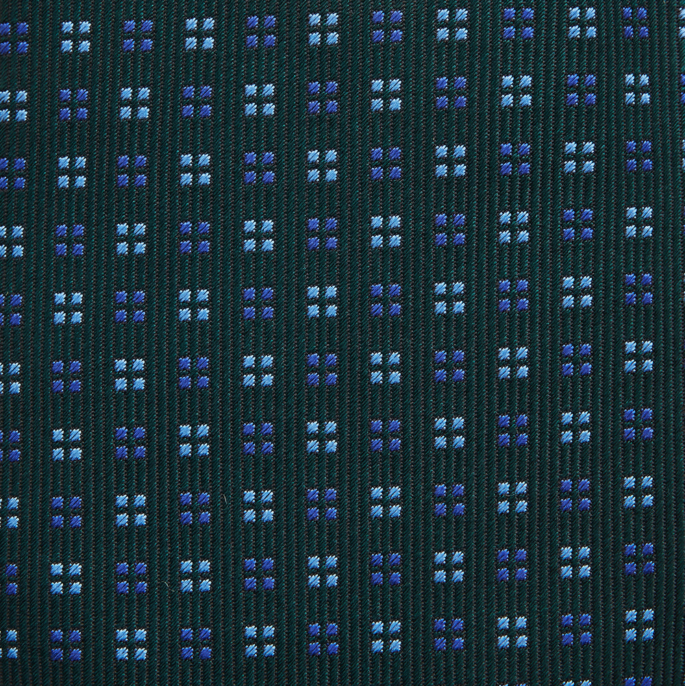 The MINI SQUARE SPOT FOREST GREEN BLUE TIE by Turnbull & Asser is a classic men's accessory, featuring a rolled-up green silk design with small blue geometric patterns—perfect for the modern gentleman.