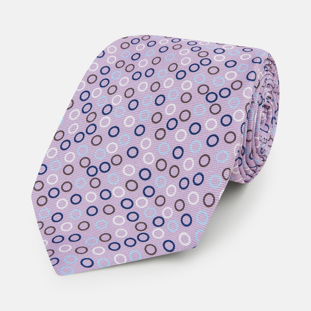The Turnbull & Asser Multi-coloured Circle Lilac Silk Tie features overlapping blue, purple, and white circles on fine English silk—ideal for elevating smart outfits. Shown rolled against a plain white background.
