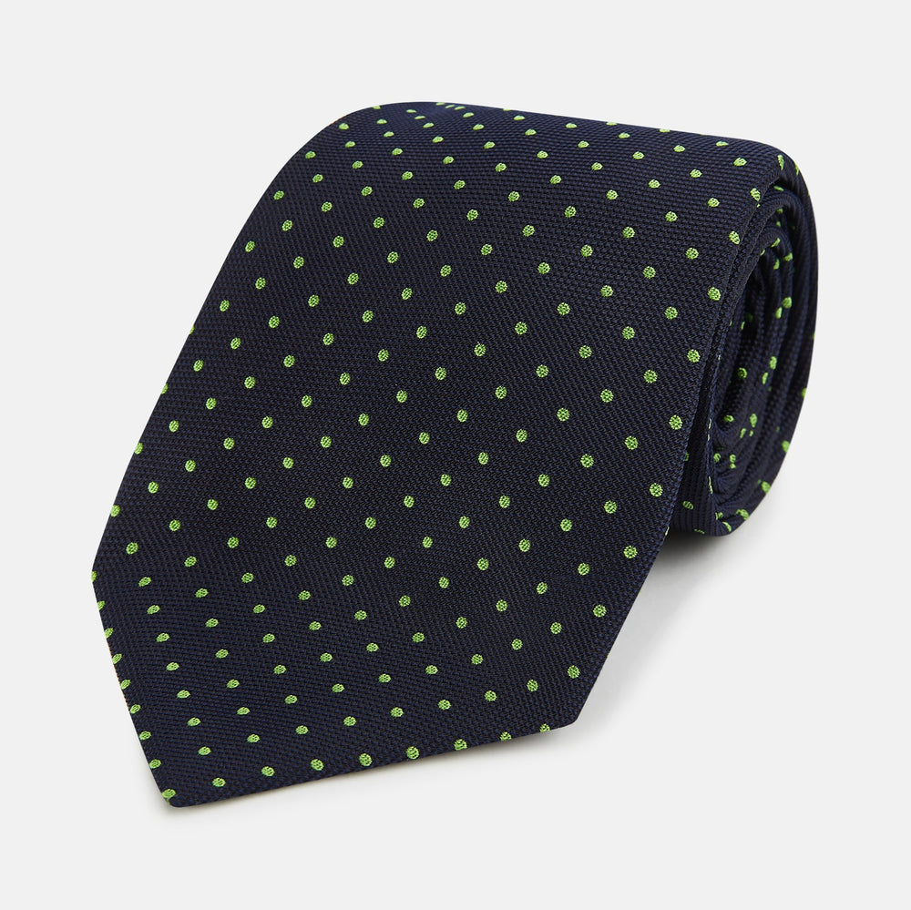 The Turnbull & Asser Green and Navy Micro Dot Silk Tie features small green dots on a navy silk background, displayed rolled up on white.