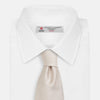 View 2 of product The Turnbull & Asser HORIZONTAL TWILL VELLUM TIE, a light beige silk necktie with a subtle ribbed texture, is shown rolled up on a white background—an essential finishing touch for smart attire.