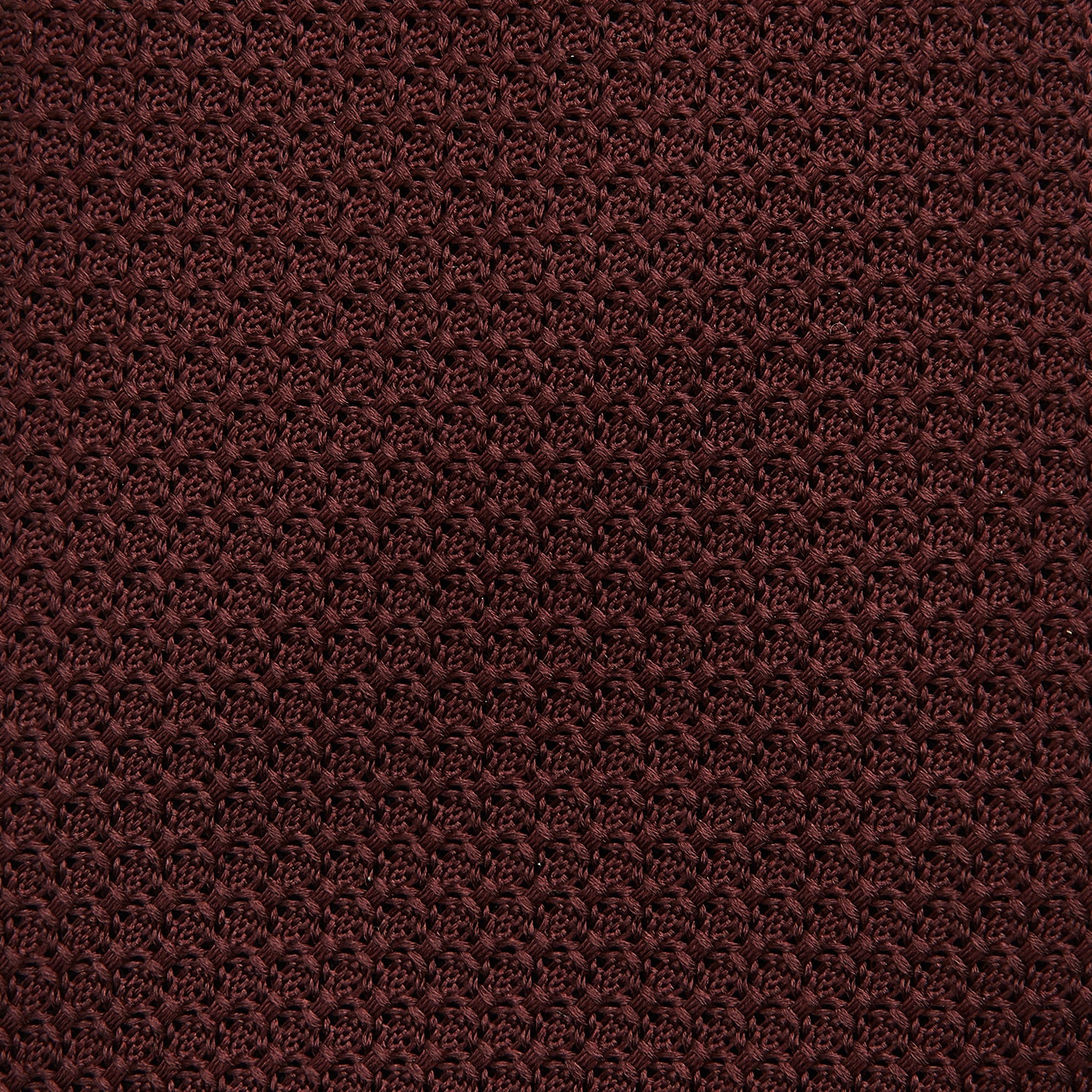 View 3 of product The Turnbull & Asser Dark Red Knitted Tie, featuring a textured finish, is shown rolled up against a white background—a stylish and versatile accessory ideal for the modern gentleman.