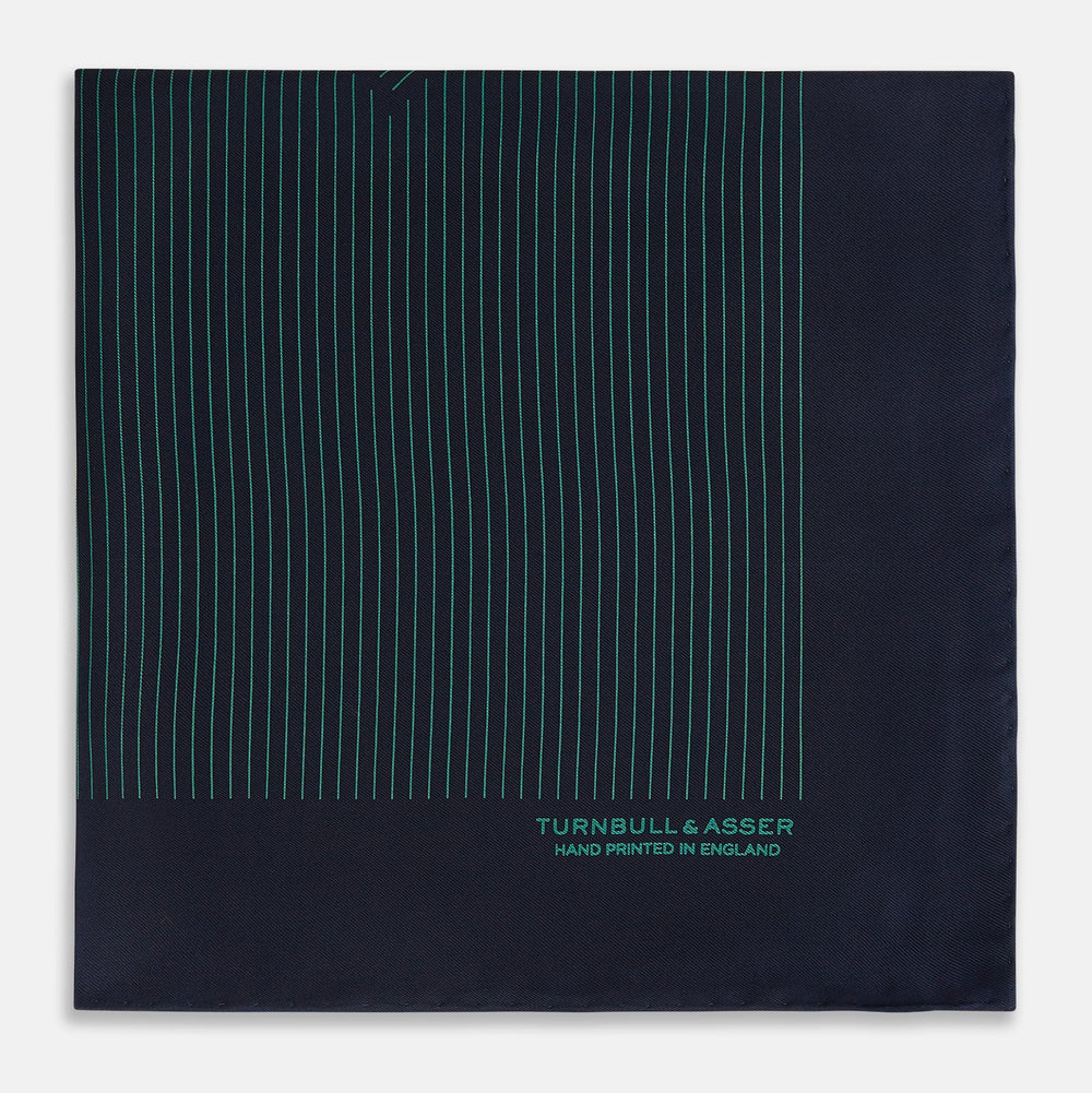 The Turnbull & Asser Navy and Hunter Green Stripe Silk Pocket Square features thin green stripes, hand-rolled edges, and "TURNBULL & ASSER HAND PRINTED IN ENGLAND" in green on the bottom right corner.