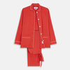View 1 of product The Turnbull & Asser Women's Coral Pink Silk Thelma Pyjama Set features a long-sleeve button-up top with two front pockets and matching drawstring pants, shown on a white background.