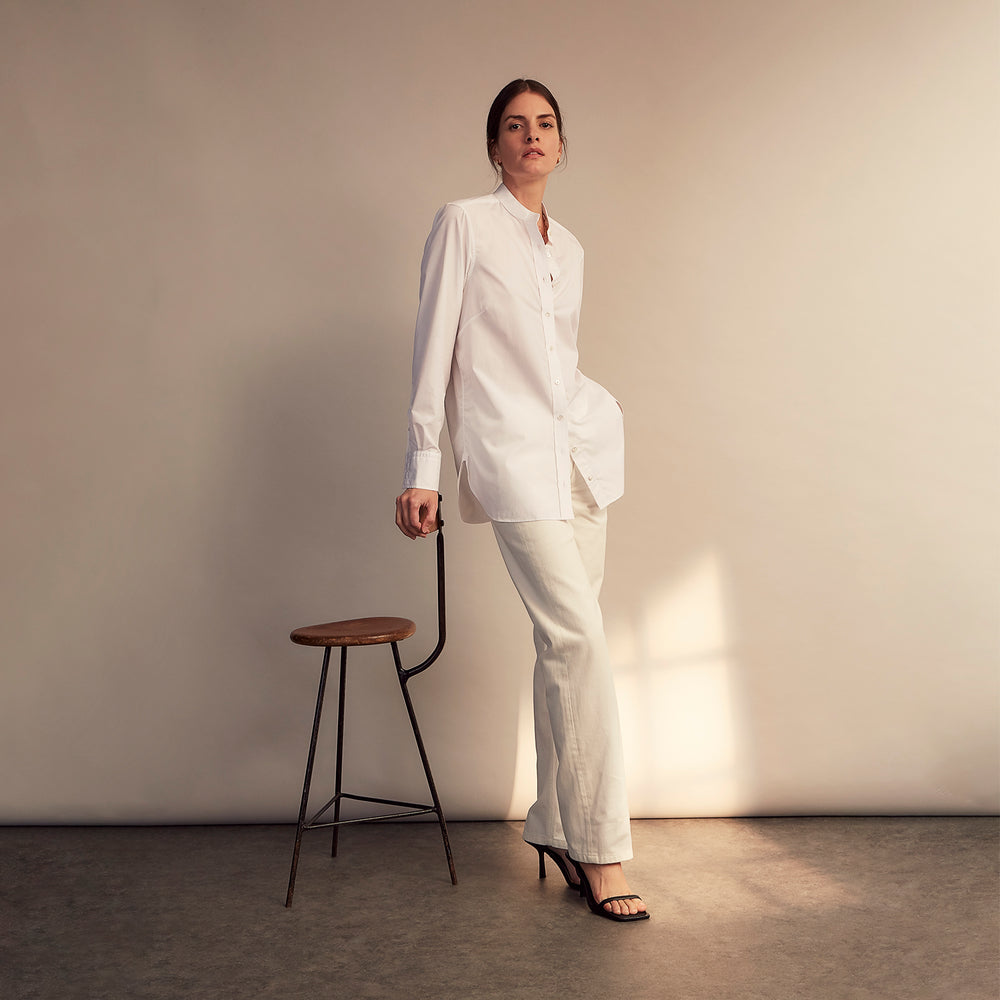 The White Cotton Lauren Shirt by Turnbull & Asser, featuring a stand collar, button-down front, and elongated body, is laid flat on a plain white background.