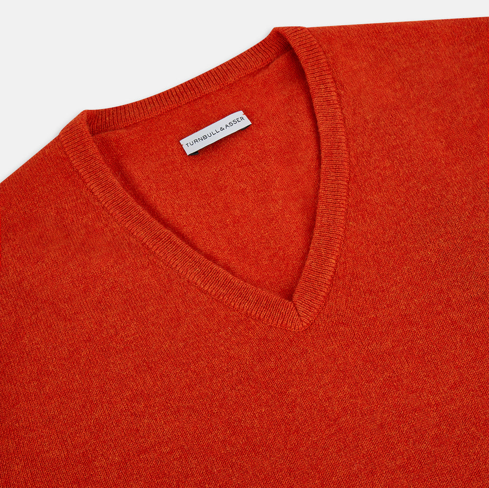 The Turnbull & Asser Red Orange Cashmere V-neck Jumper features long sleeves, ribbed cuffs and hem, displayed on a plain white background—a stylish knitwear essential for any wardrobe.
