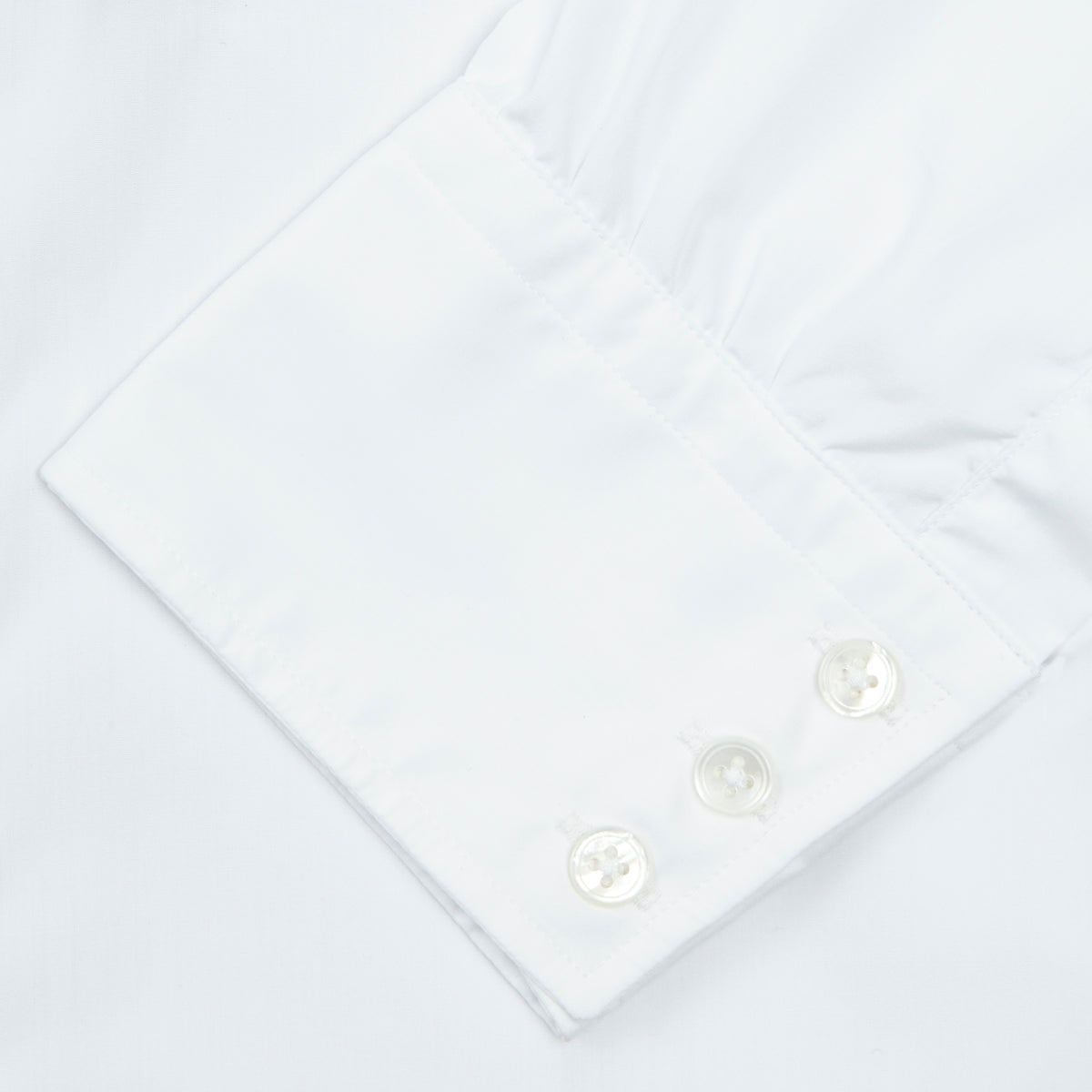 View 6 of product A neatly folded Turnbull & Asser Two-Fold 200 White Cotton Shirt with a Regent collar and 3-button cuffs, crafted from breathable fabric, is displayed on a light grey background with the label visible inside the collar.
