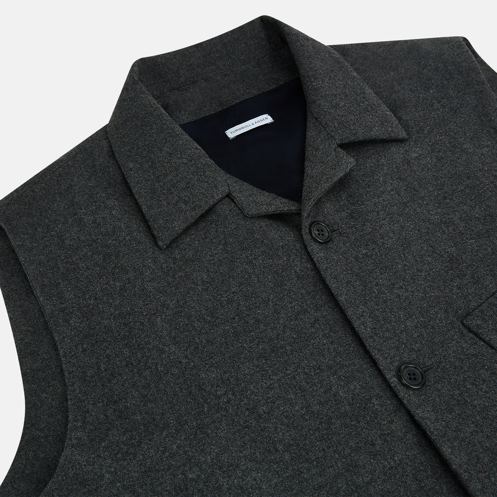The Graphite Melange Collared Single-breasted Waistcoat by Turnbull & Asser features a dark gray hue, front buttons, collar, two zippered side pockets, and a chest pocket—perfect for winter. Shown on a plain white background.