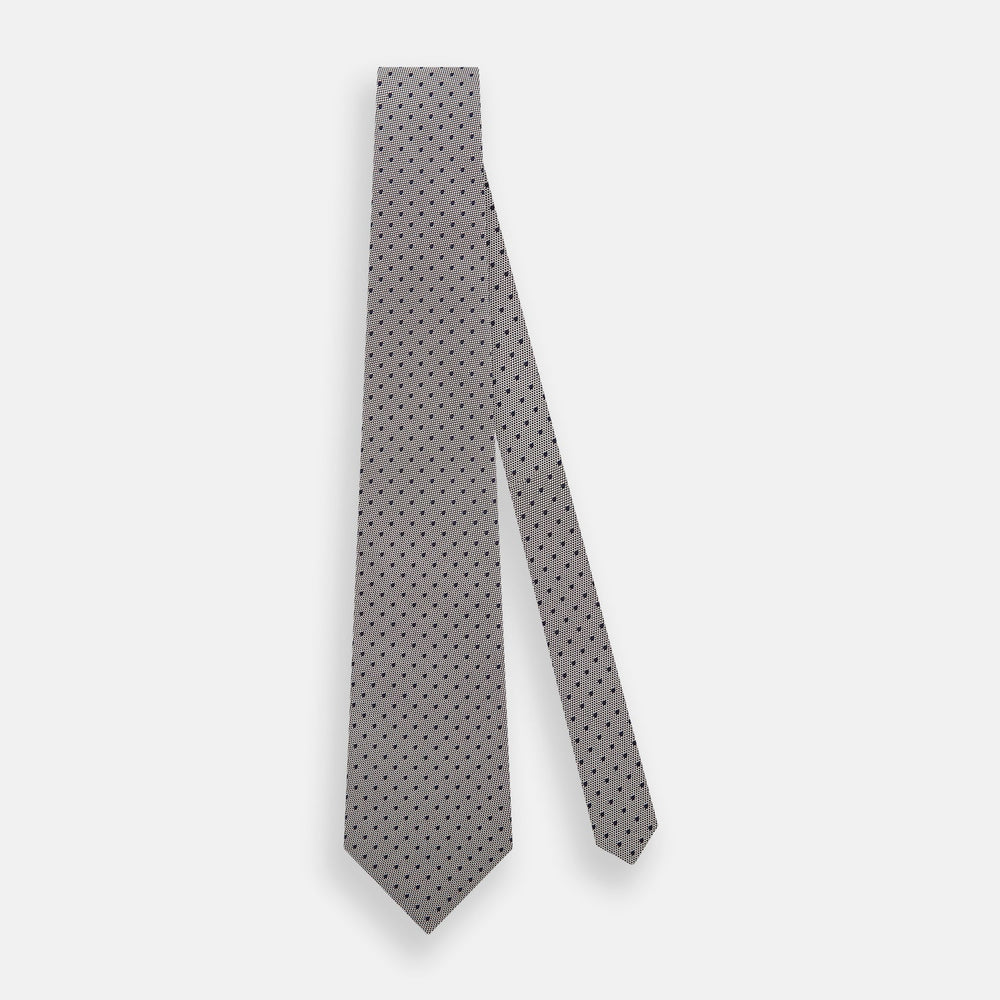 The Turnbull & Asser Navy and Lilac Micro Dot Silk Tie is shown rolled up on a white background, featuring a refined pattern of small lilac dots on navy silk.