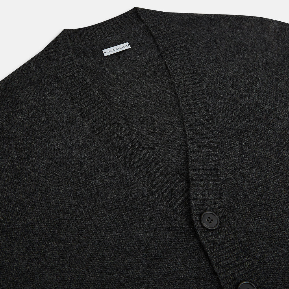 The Turnbull & Asser Dark Grey Melange Cashmere Cardigan features long sleeves, ribbed cuffs and hem, and two front pockets, shown on a plain white background.