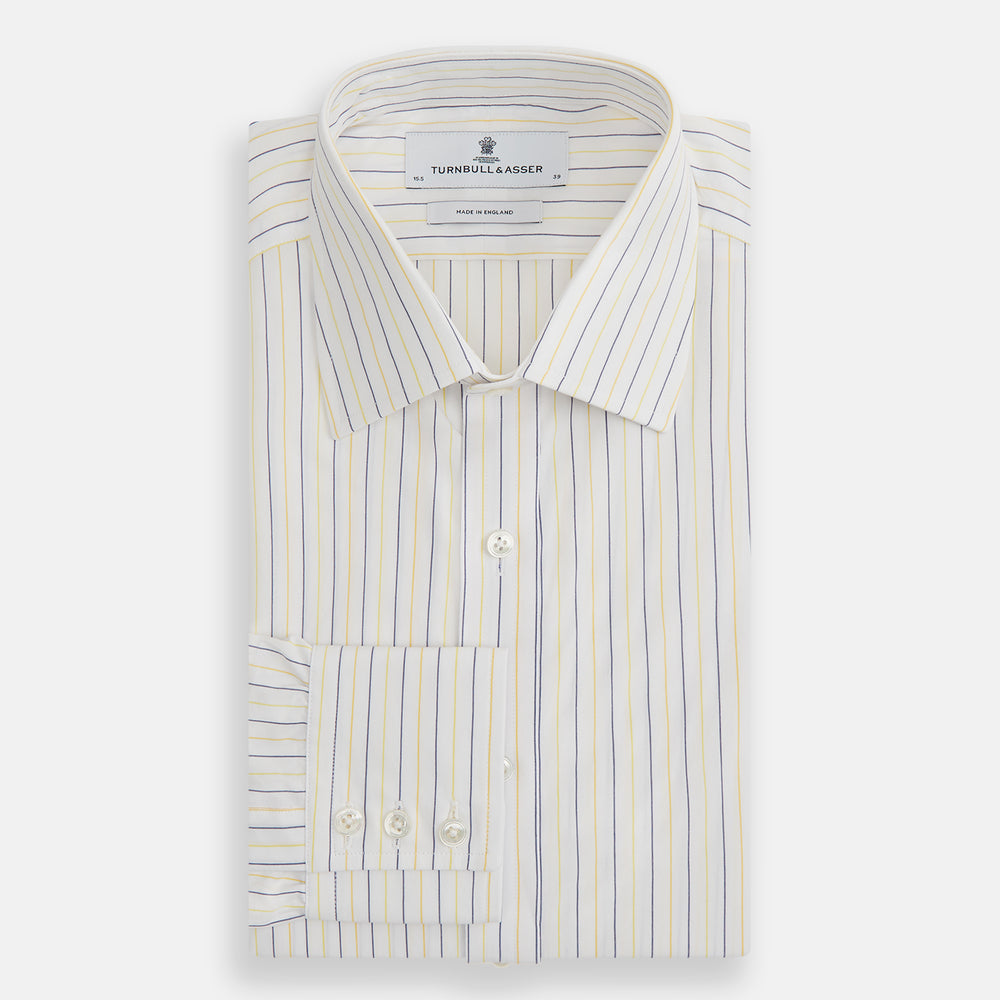 The Turnbull & Asser Yellow Double Pinstripe Mayfair Shirt, a long-sleeved, button-up with thin blue and yellow stripes on white, classic T&A collar, and buttoned cuffs, is laid flat on a white surface.