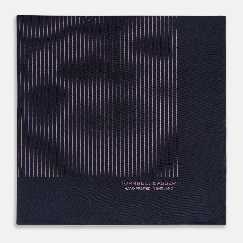 A navy silk pocket square with thin, even purple stripes and hand-rolled edges from Turnbull & Asser, featuring "Turnbull & Asser Hand Printed in England" printed in the corner.